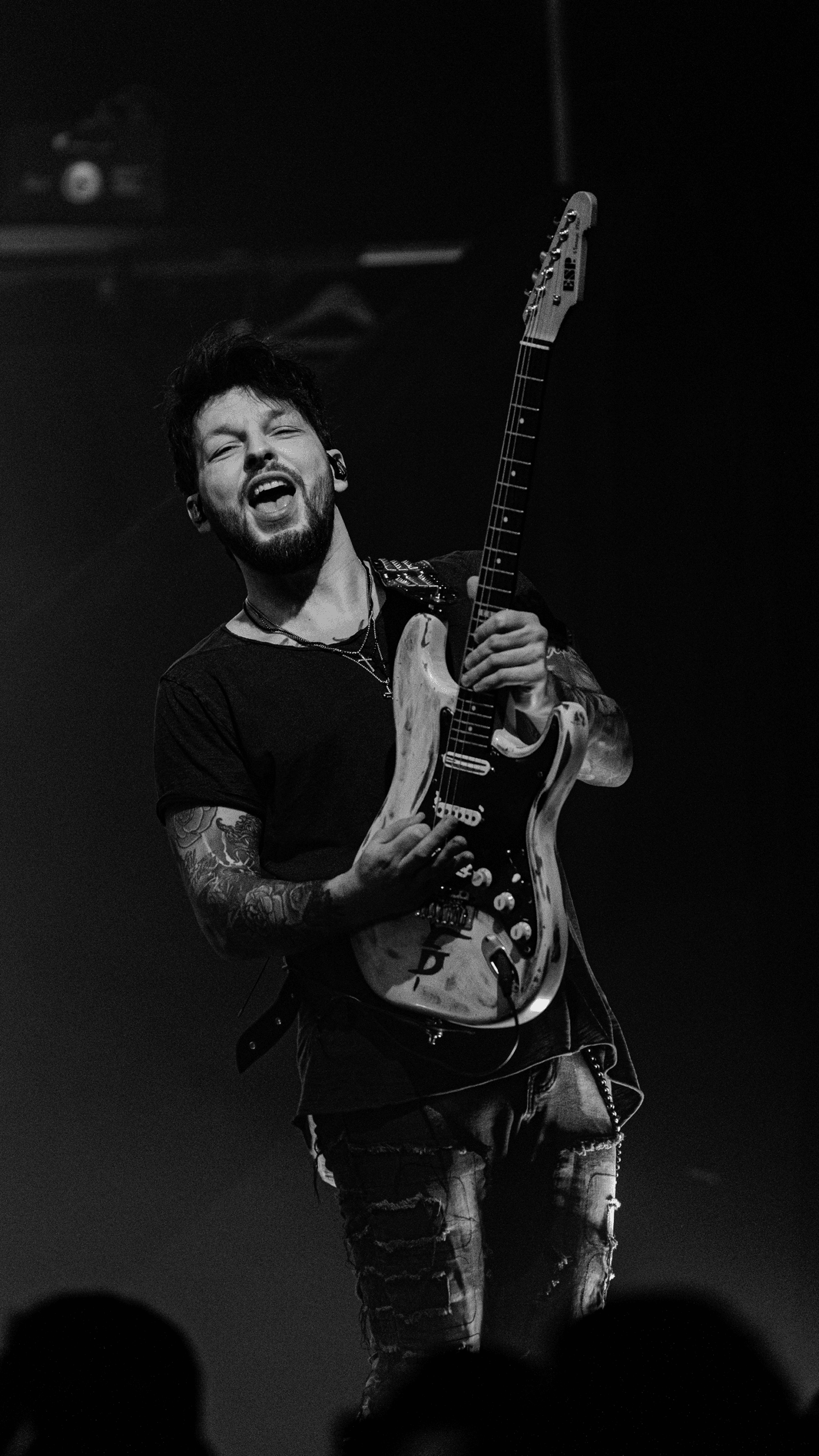 Dee Dammers playing electric guitar passionately on stage during a concert.